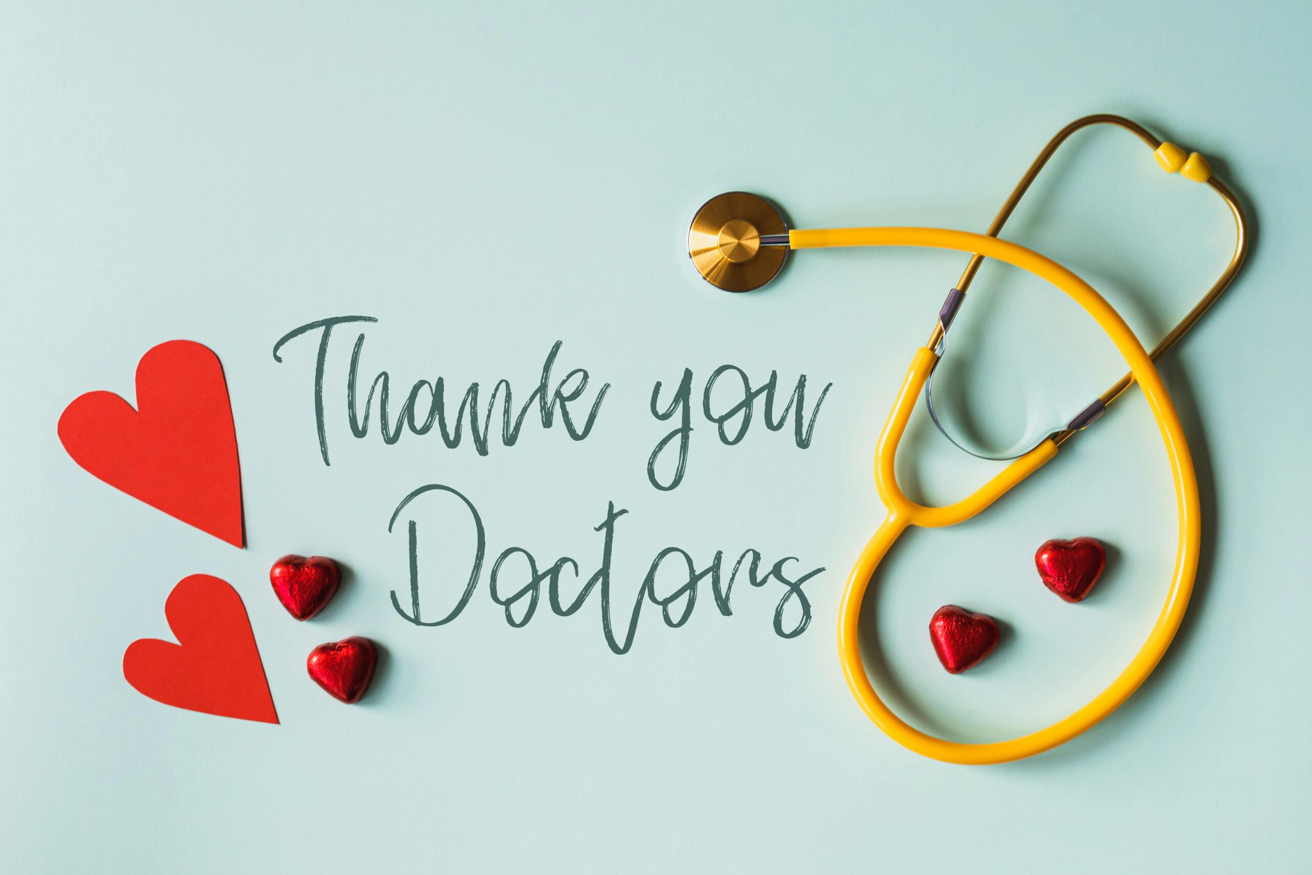 A stethoscope with hearts and 'Thank You Doctors' inscription on a blue background.